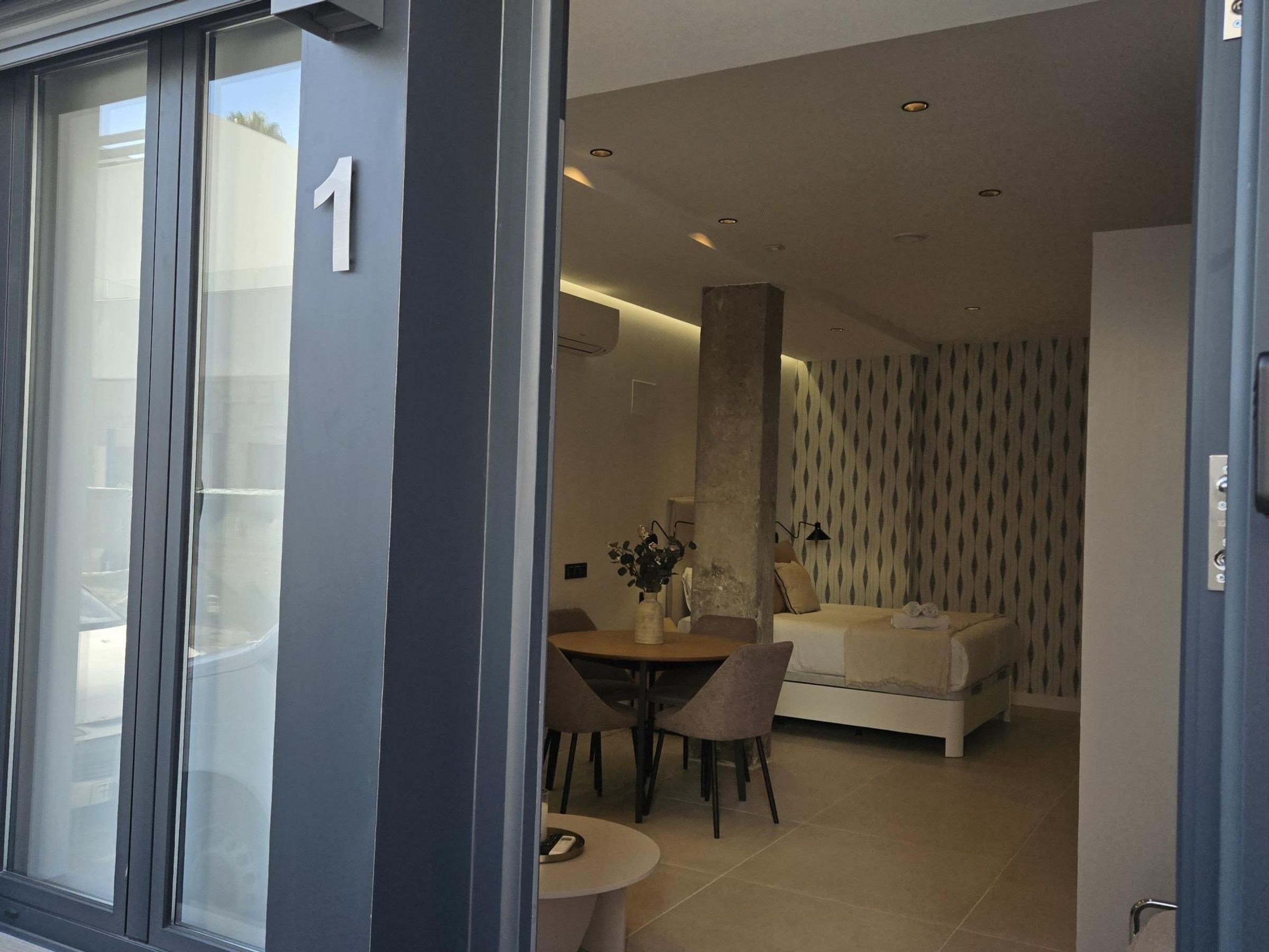 A modern interior with a dining area, a sofa, and a patterned wall.