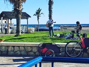 Een strandlandschap met een kiosk, palmbomen en een muzikant die gitaar speelt.