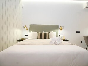 A hotel room with a large bed, two bedside tables, a headboard, and a wall-mounted lamp. - Cozy studio near beach - 4 guests (Málaga)