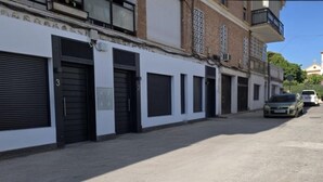 Eine Straße mit geschlossenen Geschäften, einem unbefestigten Weg und geparkten Autos.