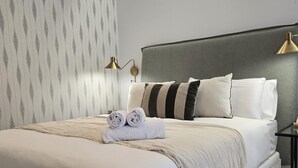 Ein ordentlich bezogenes Bett mit Kopfteil, Kissen und einem gefalteten Handtuch.