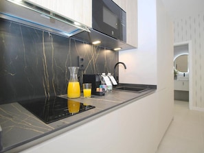 A modern kitchen with a black countertop, a built-in microwave, and a stainless steel range hood. - Cozy studio near beach - 4 guests (Málaga)