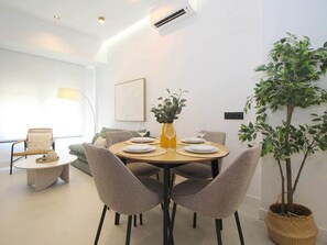 Un coin repas avec une table ronde, quatre chaises, un vase avec des fleurs et une plante en pot.