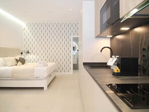 Een moderne hotelkamer met een bed, een kitchenette en een badkamer.