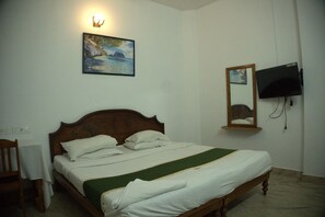 Una habitación de hotel con una cama de madera, un cuadro en la pared, un televisor y un espejo.