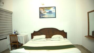 A hotel room with a bed, a chair, a small table, and a painting on the wall.