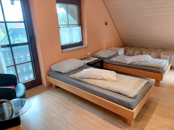 A room with two beds, a small table, and a window with curtains.