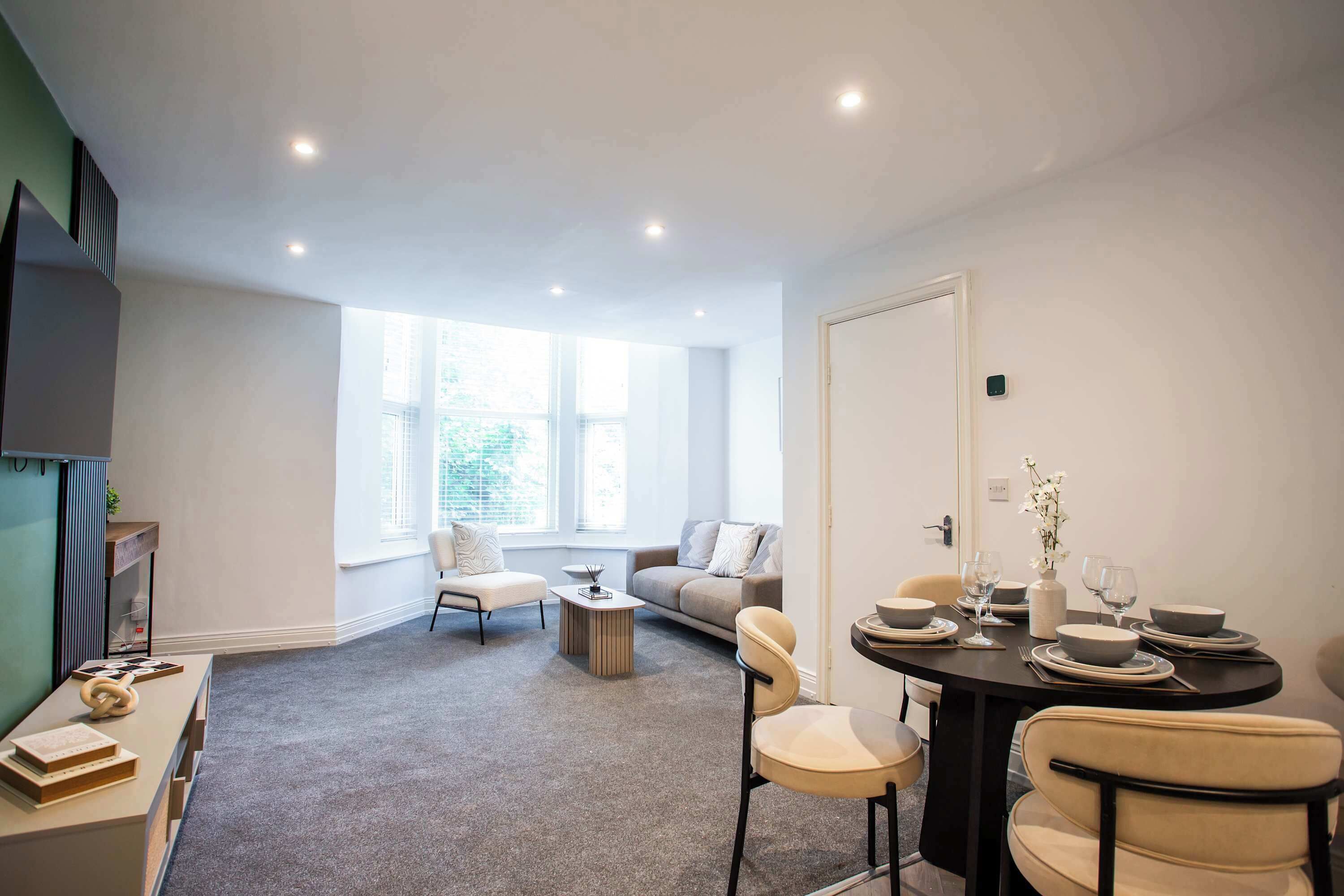 Una sala de estar moderna con comedor, ventanas amplias y vistas a zonas verdes.