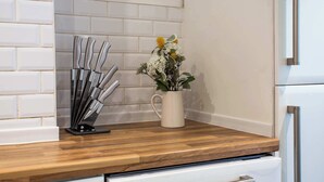 A kitchen counter with a knife block, a potted plant, and a white refrigerator. - Vacant Nests The Esplinade City Centre Wifi (Sunderland)
