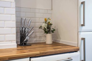 A kitchen counter with a knife block, a potted plant, and a white refrigerator. - Vacant Nests The Esplinade City Centre Wifi (Sunderland)