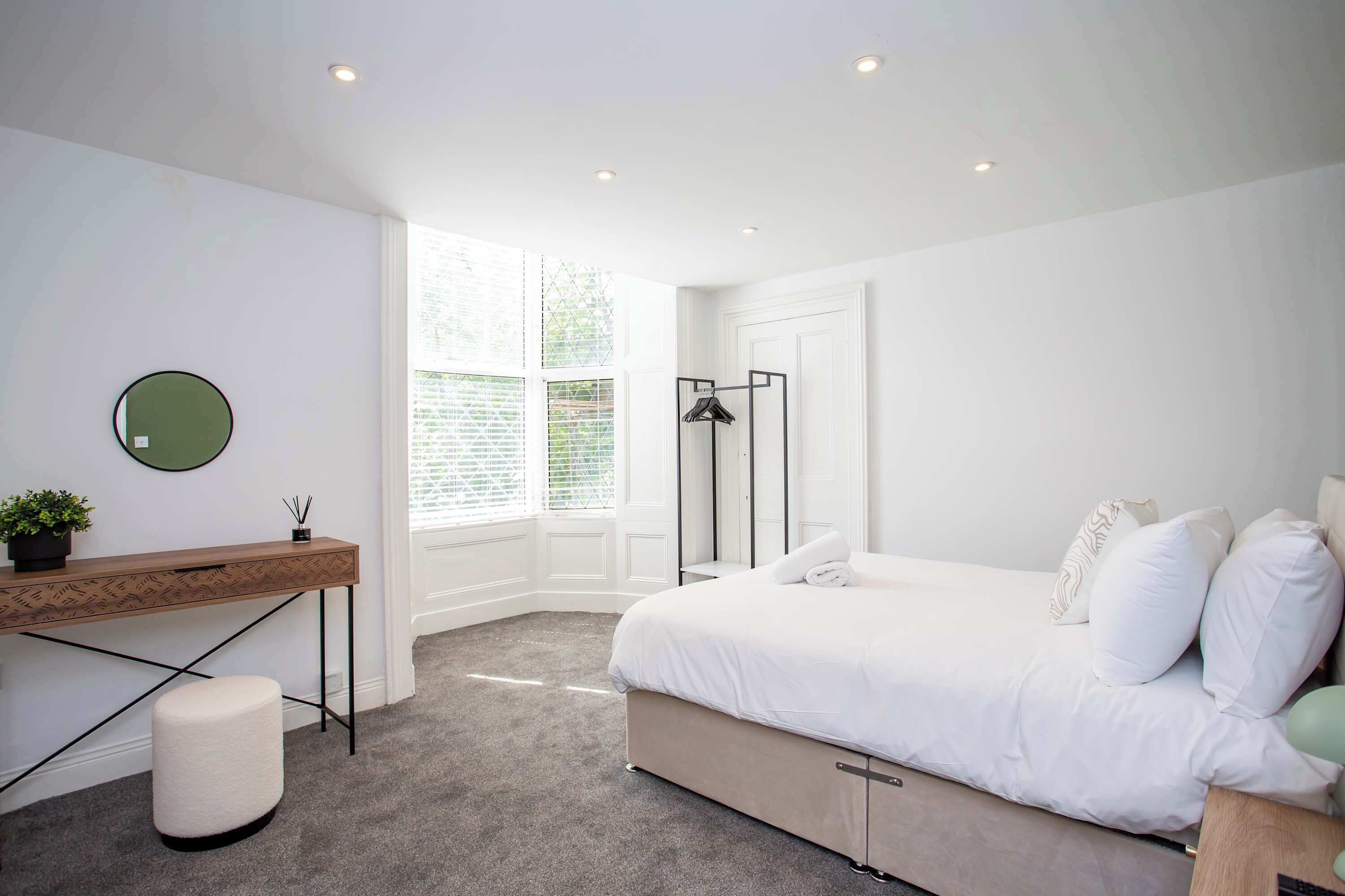 Un dormitorio con cama, mesita de noche y escritorio con silla.
