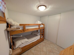 Ein Stockbett mit Holzrahmen, weißer Bettwäsche und einer Deckenleuchte.