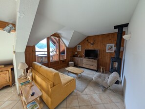 A cozy loft-style living room with a sofa, TV, and fireplace. - Duplex with mountain view - 6 guests (Montgenèvre)