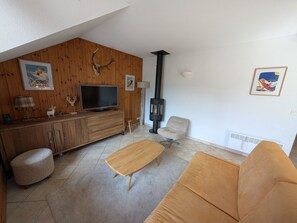 A living room with a wooden cabinet, TV, sofa, ottoman, and a fireplace. - Duplex with mountain view - 6 guests (Montgenèvre)