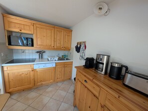 A compact kitchen with wooden cabinets, a microwave, a coffee maker, and a toaster. - Duplex with mountain view - 6 guests (Montgenèvre)