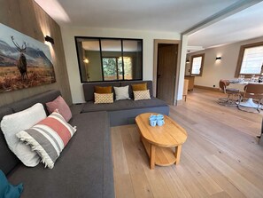 Un saló modern amb un sofà modular, una taula de centre de fusta i una zona de menjador amb taula i cadires.