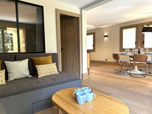 A modern living room with a sofa, a dining area with a table and chairs, and a wooden floor. - Family apartment near slopes - 8 guests (Méribel)