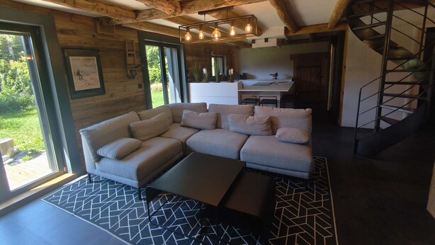 Ein modernes Wohnzimmer mit Ecksofa, Treppe und Küchenbereich.