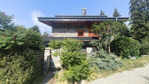 Ein modernes Haus mit Natursteinfassade, einer flachen Dachkonstruktion und einem großen Fenster.
