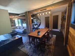 Ein modernes Interieur mit einem Holzes Esstisch, einer Couch und einer Treppe.