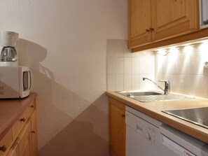 Eine Küche mit Holzausstattung, einer Mikrowelle, einer Kaffeemaschine, einem Spülbecken und einem Geschirrspüler.