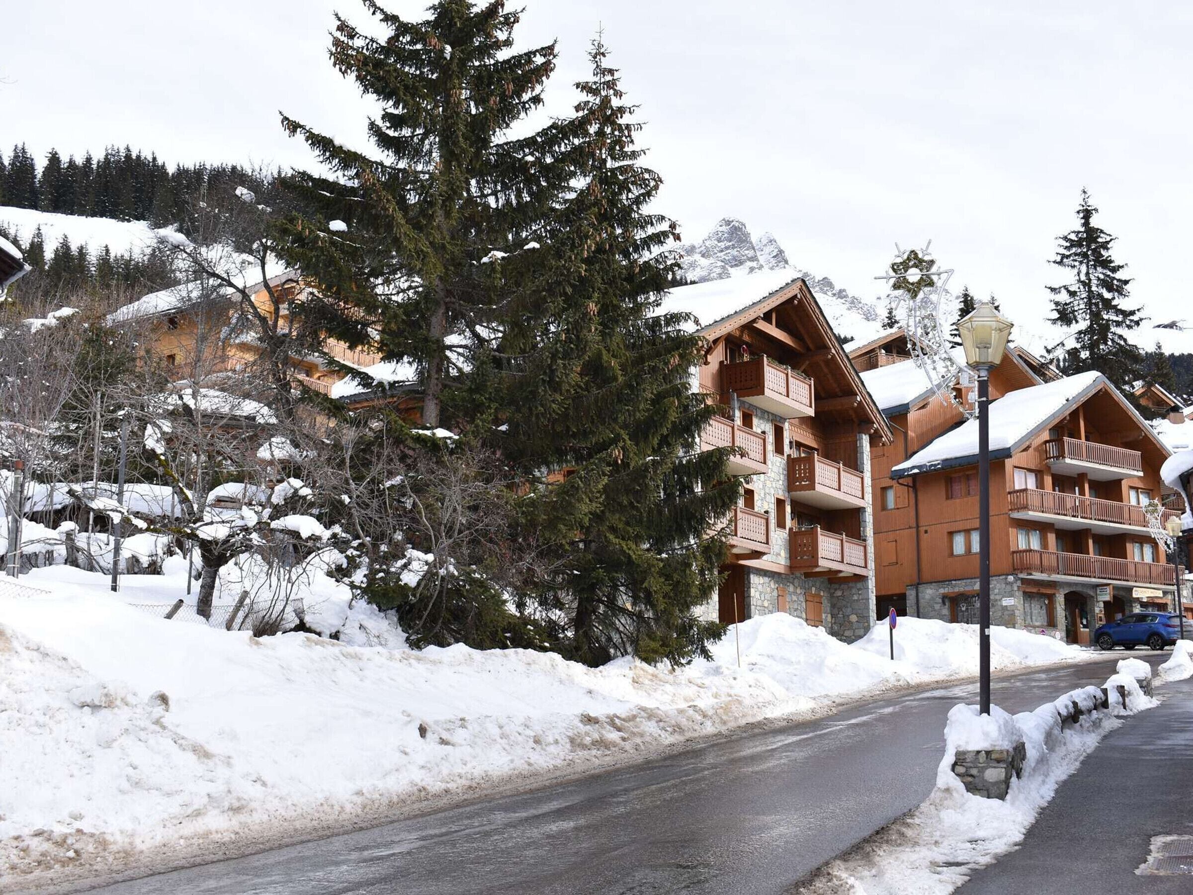 A snow-covered mountain lodge with multiple balconies and a road in the foreground.