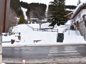 A snow-covered street with a wooden fence, a staircase leading to a building, and a crosswalk. - Spacious apartment, mountain view - 6 guests (Méribel)