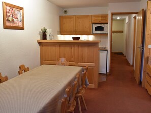 A compact kitchen with wooden cabinets, a microwave, and a small refrigerator. - Spacious apartment, mountain view - 6 guests (Méribel)