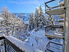 Ein mit Schnee bedeckter Balkon mit Blick auf eine verschneite Berglandschaft.