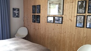 Une pièce comprenant un lit, une chaise et un mur en bois orné de tableaux encadrés.