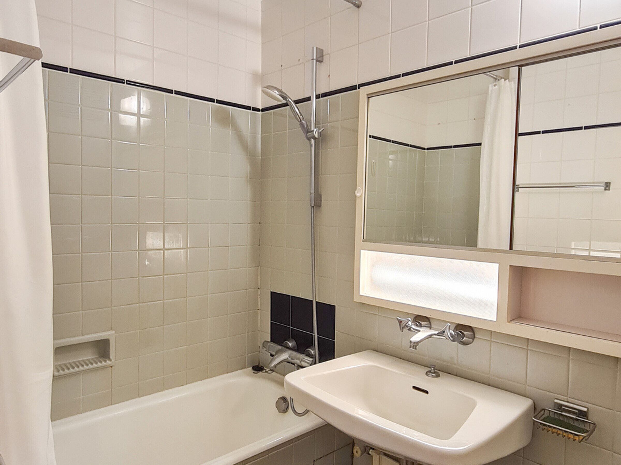 A bathroom with a bathtub, a sink, a shower, and a mirror.