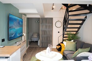 Uma sala de estar moderna com uma TV de tela plana, um sofá, uma mesa de centro e uma escada.