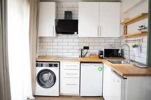 A compact kitchen with a washing machine, dishwasher, microwave, and a coffee maker. - Stylish Duplex with Private Terrace near Taksim Sleeps6 Deniz Apart with cool AC (Istanbul)