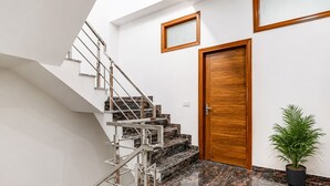 A modern interior with a staircase, a wooden door, and a potted plant. - PRISHA HOTAL AND RESTAURANTS (Zirakpur)
