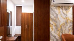 A hotel room with a wooden wardrobe, a bench, a sofa, and a marble-patterned wall. - PRISHA HOTAL AND RESTAURANTS (Zirakpur)