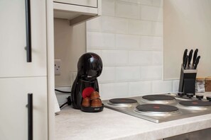 A kitchen with a coffee machine, a knife block, and a tiled backsplash.