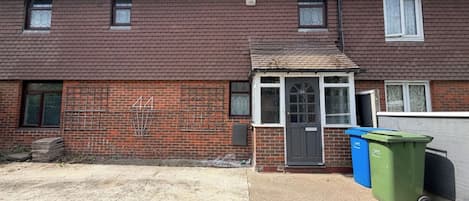 A residential building with a brick facade, a front door, and a small porch area.