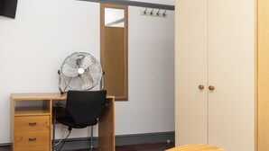 A bedroom with a wooden desk, a chair, a fan, a wardrobe, and a mirror. - Spacious 4BDR House by Canada Water (Greater London)