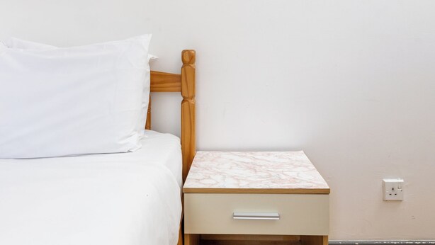 A bed with white bedding, a wooden headboard, and a bedside table with a marble top. - Spacious 4BDR House by Canada Water (Greater London)