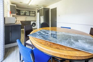 A dining area with a round table, chairs, and a kitchen in the background. - Spacious 4BDR House by Canada Water (Greater London)