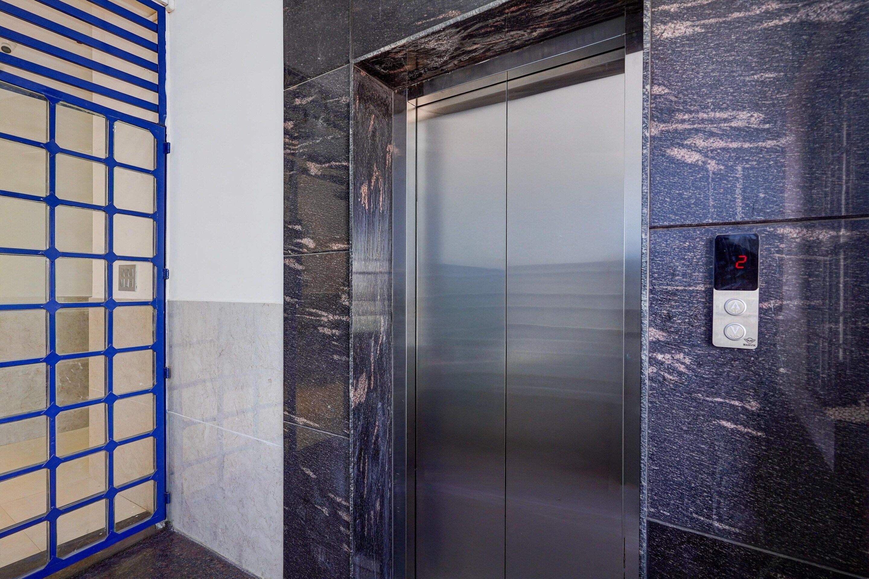 An elevator with a digital display, a blue metal gate, and marble walls.