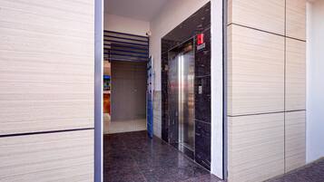 Un pasillo con un ascensor cerrado y una puerta azul.
