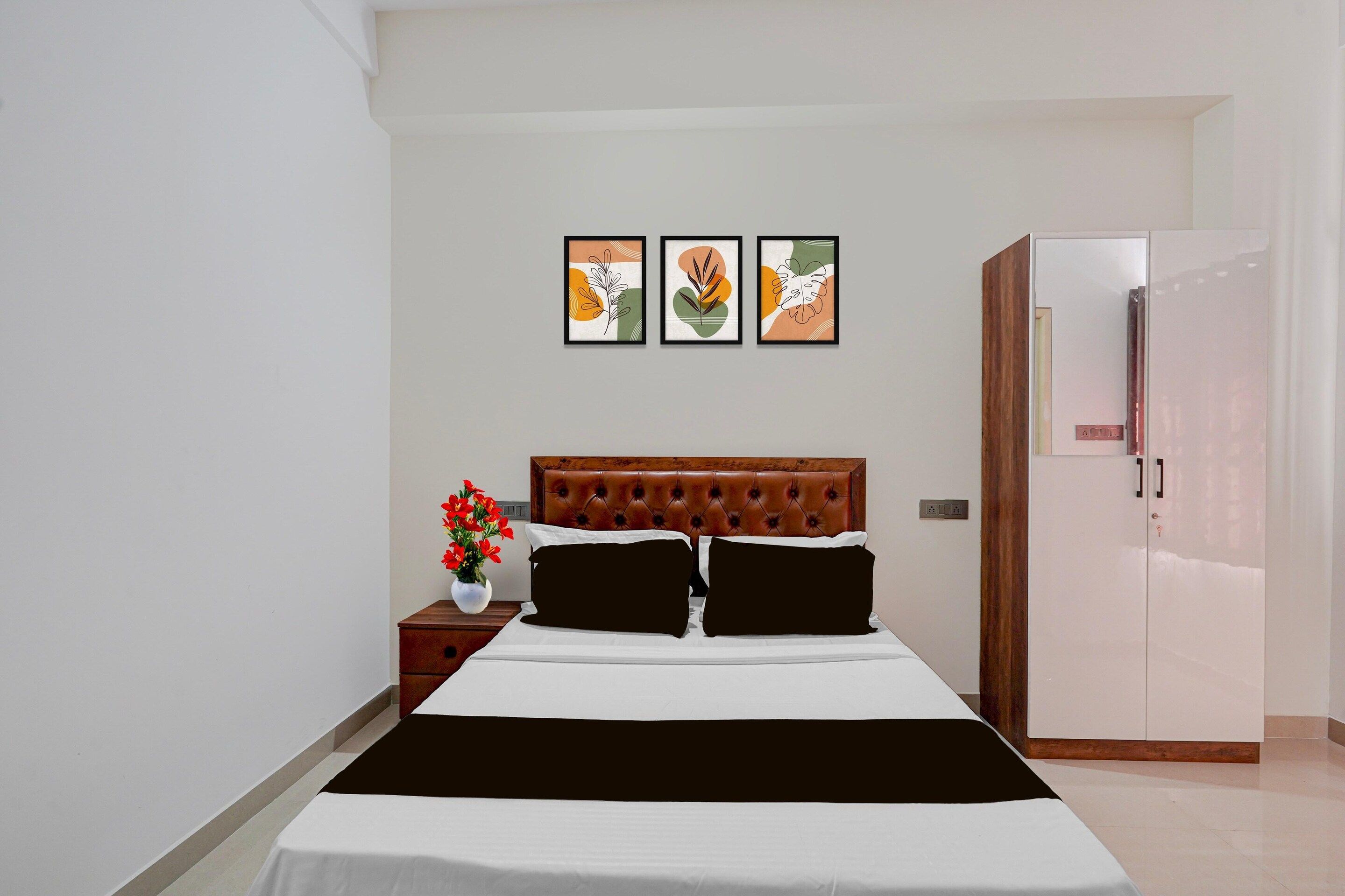 A bedroom with a bed, a nightstand with a vase of flowers, and a wardrobe.