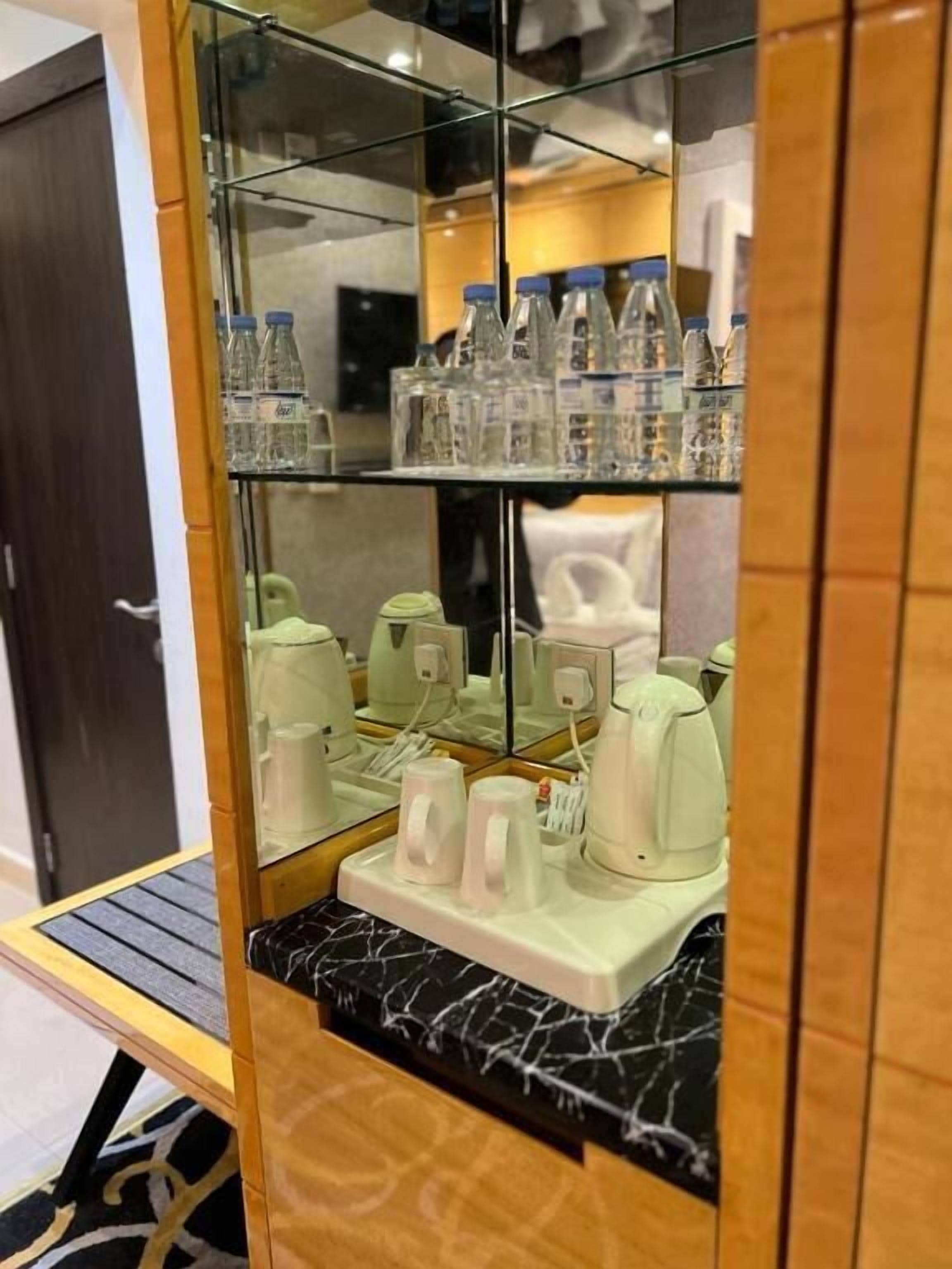 A glass-fronted cabinet with water bottles and a coffee maker.