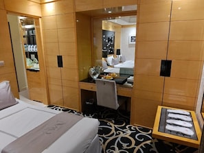 Habitación de hotel con cama, escritorio, espejo y zapatero.