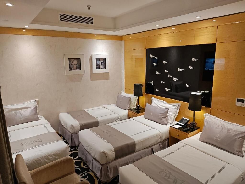 A hotel room with three beds, a wooden headboard, and a wall-mounted artwork of birds.