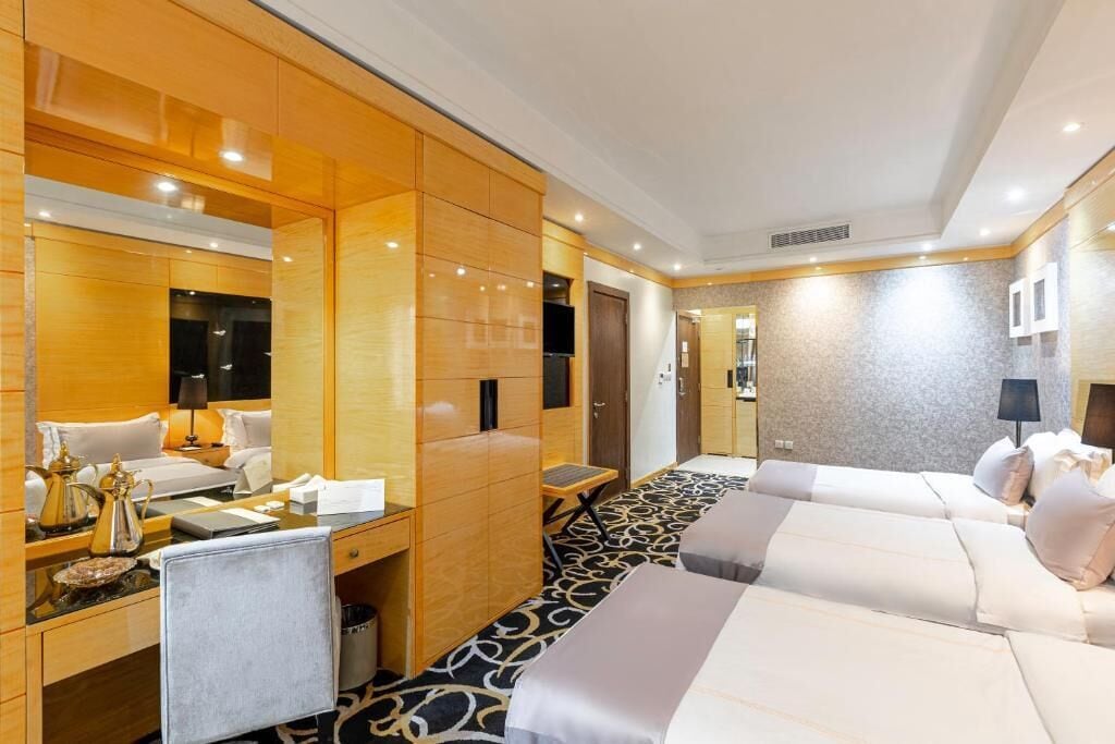 Une chambre d’hôtel avec un grand lit, un bureau avec une chaise, un miroir et une armoire.