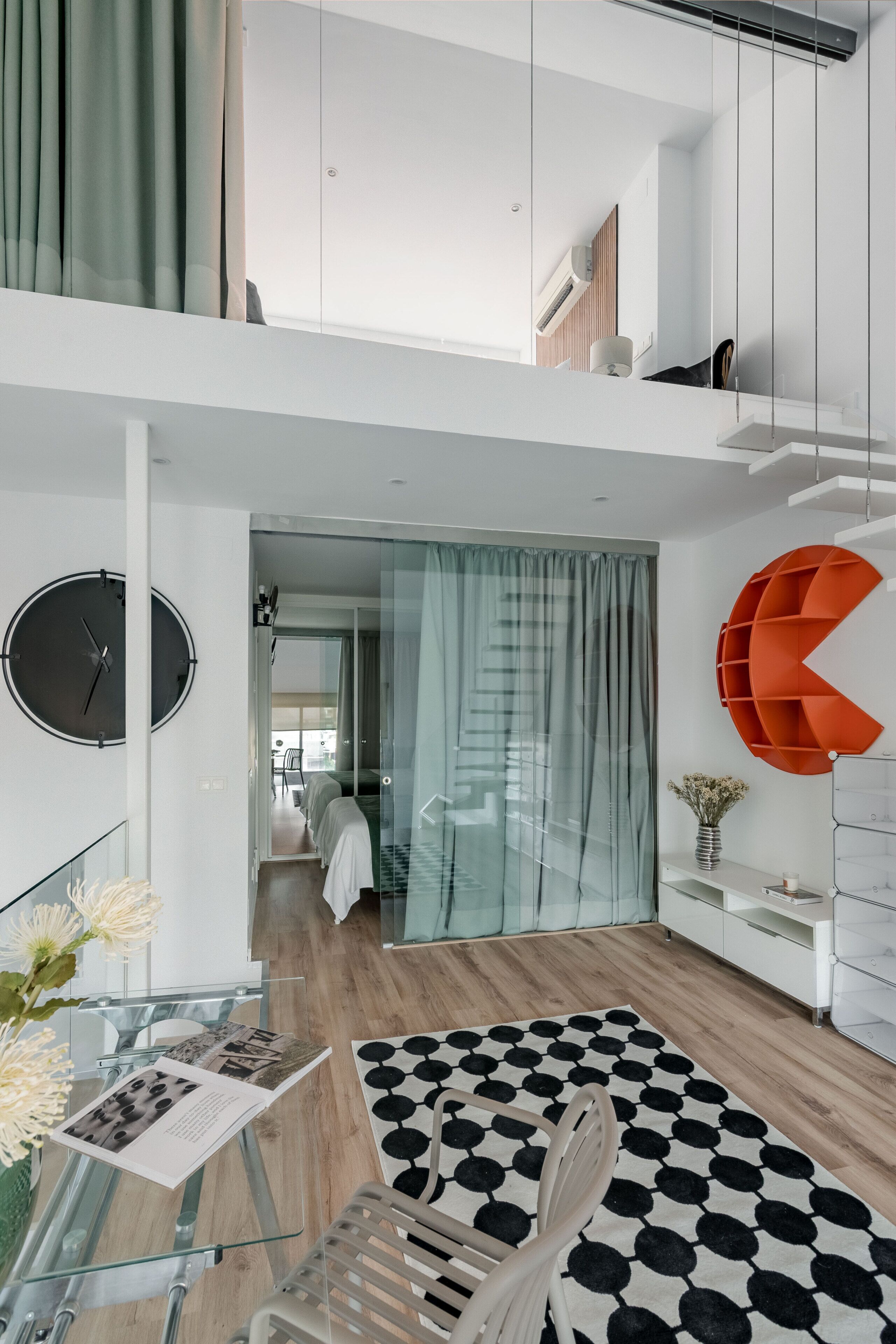 Een modern interieur met een trap, een ronde klok en een opvallende oranje plank.
