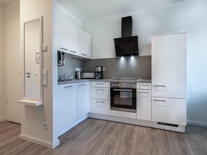 Eine moderne Küche mit weißen Schränken, einem Backofen und einer Kaffeemaschine.