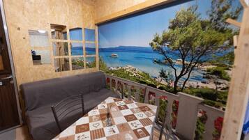 Ein Zimmer mit Blick auf Strand und Meer, eine Couch, ein Tisch mit kariertem Tischläufer und ein Spiegel an der Wand.